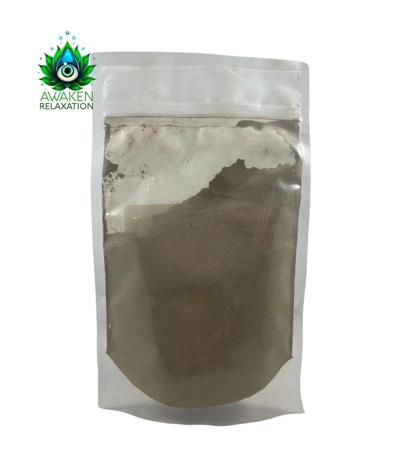 Puede incluir: Una bolsa de pl&aacute;stico transparente con base, llena de un polvo fino de color marr&oacute;n claro. La parte superior de la bolsa cuenta con un cierre herm&eacute;tico. En la esquina superior izquierda, un logotipo muestra una flor de loto verde con un ojo azul y el texto AWAKEN RELAXATION.