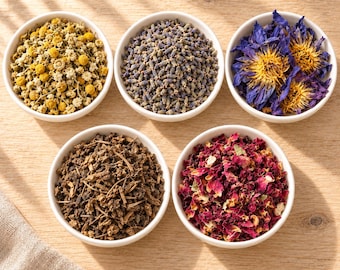 May include: Five white ceramic bowls filled with dried botanical ingredients. The bowls contain yellow chamomile flowers, purple lavender buds, blue lotus flowers, brown woody root pieces, and vibrant pink rose petals arranged in a circular pattern.