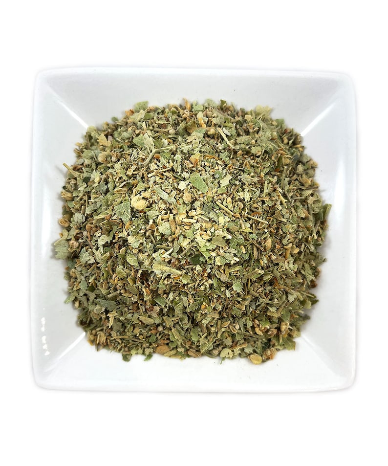 May include: A white ceramic dish filled with a mound of dried green and brown herbs.