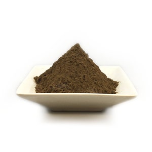 May include: A small white square dish filled with a mound of dark brown powder.