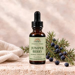 May include: A brown glass dropper bottle of Awaken Herbs Juniper Berry herbal tincture, 1 fl oz (30 mL). The label features a sun icon and text. Beside the bottle are green juniper needles and dark blue berries.