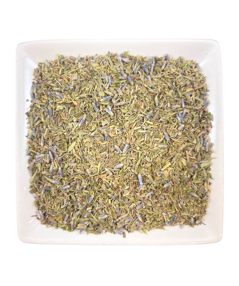 Pu&ograve; includere: Un piatto quadrato bianco pieno di un mix di erbe secche e fiori di lavanda. Le erbe sono un mix di verde e marrone, e i fiori di lavanda sono di un viola chiaro.