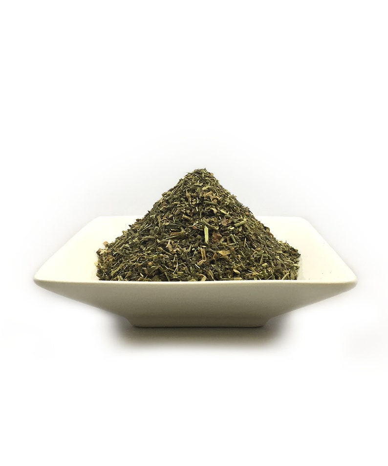 May include: A pile of dried green herbs in a white square dish. The herbs are loose and appear to be a blend of different types.