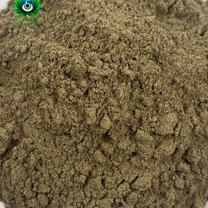 Puede incluir: Un polvo fino de tono marr&oacute;n terroso con una textura granular. En la esquina superior izquierda, un peque&ntilde;o logotipo presenta una flor de loto verde estilizada con un dise&ntilde;o de ojo central y el texto AVALON RELAXATION en letras may&uacute;sculas verdes.