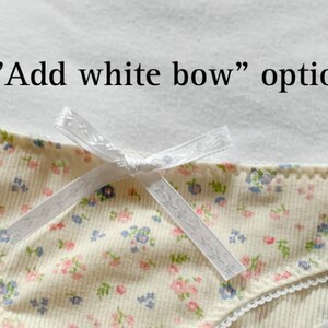 May include: A white bow with a floral print on a white background. The text "Add white bow" option is visible above the bow.