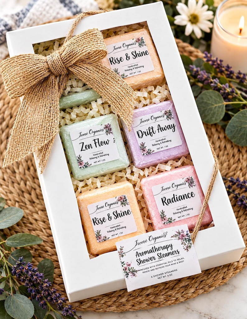 May include: A white gift box containing six square shower steamers in peach, light green, lavender, and pink. Each steamer has a label reading Rise & Shine, Zen Flow, Drift Away, or Radiance. The box is decorated with a large burlap bow and a tag.