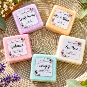 May include: Five square bath bombs in purple, orange, pink, light blue, and white. Each features a Treve Organics label with names Drift Away, Rise & Shine, Radiance, Energize, and Zen Flow, plus scent notes and a net weight of 28g.
