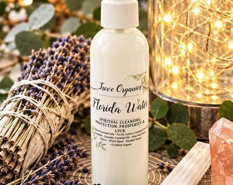 May include: A white plastic spray bottle labelled Trove Organics Florida Water, featuring text about spiritual cleansing, protection, prosperity, and luck, with a list of essential oils including neroli, lemon, cinnamon, and lavender.