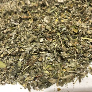 May include: A close-up of a pile of dried herbs, including green, brown, and white pieces. The herbs are loose and appear to be ready for use in a variety of applications.