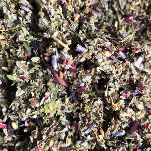 May include: A close-up of a blend of dried herbs and flowers, including lavender, hibiscus, and other botanicals. The mixture is a variety of colors, including green, purple, pink, and brown.
