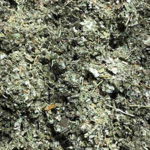 May include: Close-up of dried, green, and brown herbs. The herbs are finely chopped and appear to be a blend of different types.