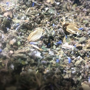 May include: A close-up of a blend of dried herbs and flowers, including lavender, for making herbal tea. The mixture is a mix of light brown, green, and purple hues.
