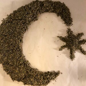 May include: A crescent moon and a star shape made from dried herbs on a white background.