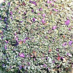 May include: A close-up of a mixture of dried herbs and flower petals. The mixture is a blend of green herbs and purple flower petals.