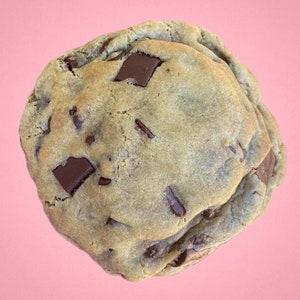 Peut inclure: Un gros cookie aux pépites de chocolat brun doré avec des pépites de chocolat noir. Le cookie est légèrement bombé et a une texture moelleuse et moelleuse.