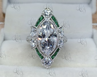 May include: A silver ring with a large marquise-shaped diamond surrounded by smaller diamonds and green emerald stones.