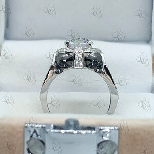 May include: A silver engagement ring with a large, round, clear center stone surrounded by smaller stones. The band is decorated with two skull-shaped designs.