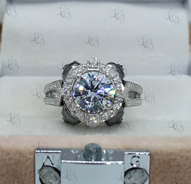 May include: A silver engagement ring with a large, round, clear center stone surrounded by a halo of smaller stones. The ring has a double band with small stones set into the band.