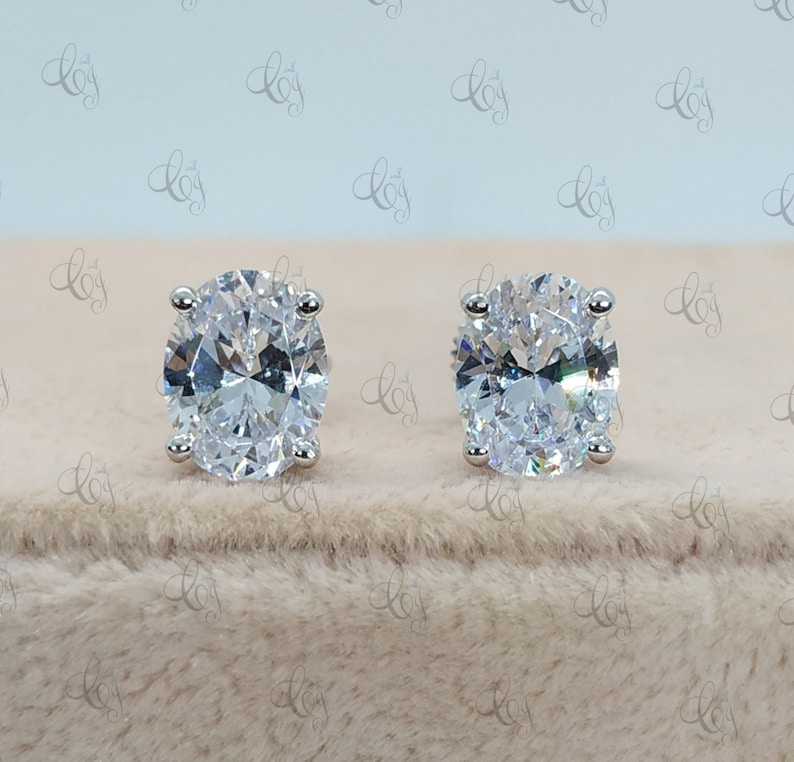 May include: A pair of silver stud earrings with large oval-shaped clear cubic zirconia stones.
