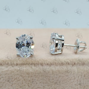 May include: A pair of silver stud earrings with large oval-shaped clear cubic zirconia stones.