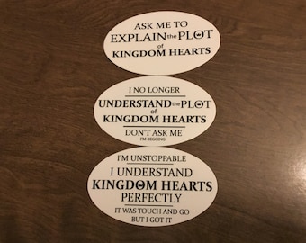 以下が含まれることがあります： キングダムハーツのビデオゲームに関する黒いテキストが書かれた3つの白い楕円形のステッカー。一番上のステッカーには「キングダムハーツのプロットを説明して」と書かれています。真ん中のステッカーには「キングダムハーツのプロットはもう理解できません。尋ねないでください、お願いします」と書かれています。一番下のステッカーには「私は止められない、キングダムハーツを完璧に理解しています」と書かれています。