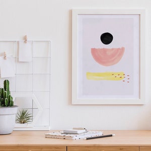 May include: A framed abstract art print with a pink half-circle, a black circle, and a yellow rectangle with orange dots on a light purple background.
