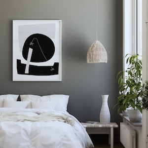 Puede incluir: Una cama blanca con un edred&oacute;n blanco y una manta blanca. Un estampado abstracto en blanco y negro cuelga de la pared sobre la cama. Una l&aacute;mpara colgante de mimbre cuelga del techo. Un jarr&oacute;n blanco se encuentra sobre una mesita auxiliar blanca junto a una planta en maceta.