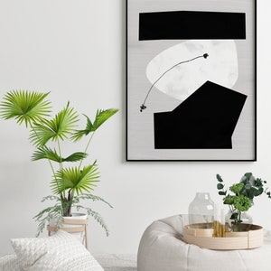 May include: A black and white abstract art print with geometric shapes and a thin line drawing of a plant. The print is framed in a black frame and is hanging on a white wall.