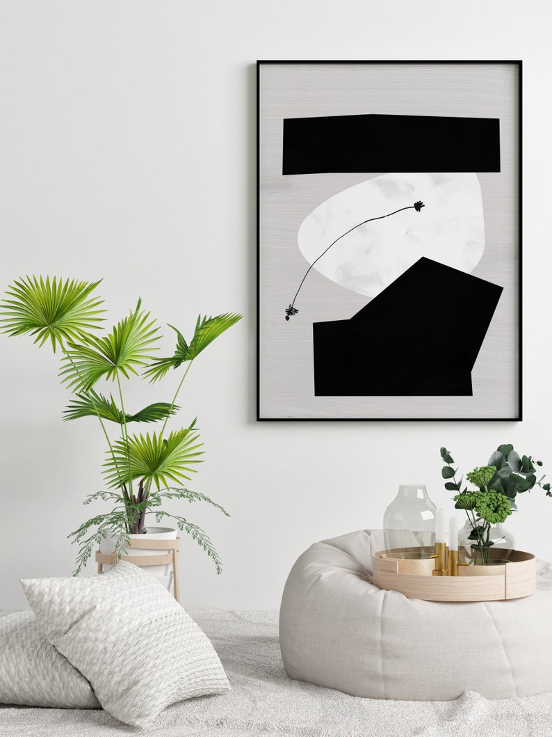 May include: A black and white abstract art print with geometric shapes and a thin line drawing of a plant. The print is framed in a black frame and is hanging on a white wall.