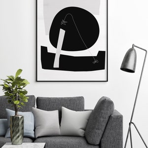 Puede incluir: Una impresi&oacute;n de arte abstracto en blanco y negro con formas geom&eacute;tricas y una l&iacute;nea fina. La impresi&oacute;n est&aacute; enmarcada en un marco negro y est&aacute; colgada en una pared blanca sobre un sof&aacute; gris.