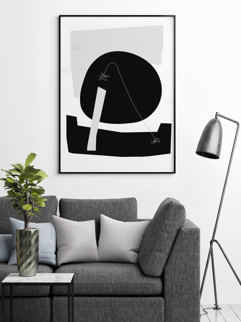 Puede incluir: Una impresi&oacute;n de arte abstracto en blanco y negro con formas geom&eacute;tricas y una l&iacute;nea fina. La impresi&oacute;n est&aacute; enmarcada en un marco negro y est&aacute; colgada en una pared blanca sobre un sof&aacute; gris.