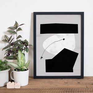 May include: Black and white abstract art print in a black frame. The print features geometric shapes and a thin line with a small black dot at the end.
