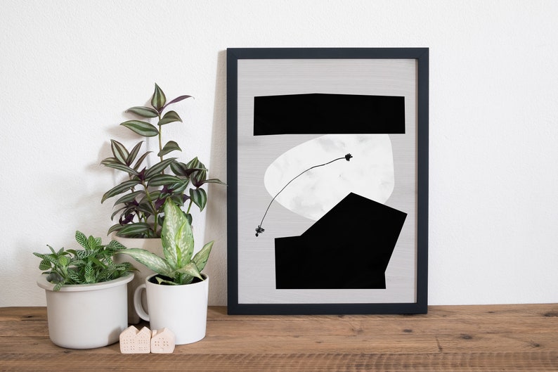 May include: Black and white abstract art print in a black frame. The print features geometric shapes and a thin line with a small black dot at the end.