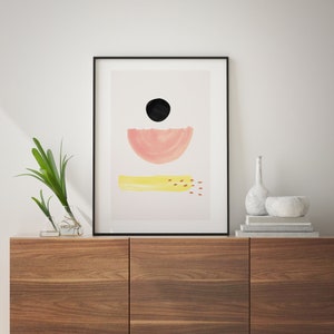 May include: A framed abstract art print with a black circle, pink half-circle, and yellow rectangle with red dots on a light pink background.