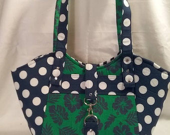 Może przedstawiać: Torba typu tote w kolorze niebieskim i białym w białe kropki, z panelem w zielony wzór kwiatowy i srebrnym zapięciem. Torba ma dwa uchwyty.