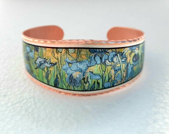 May include: A copper cuff bracelet with a colorful image of a painting of blue irises on a white background.