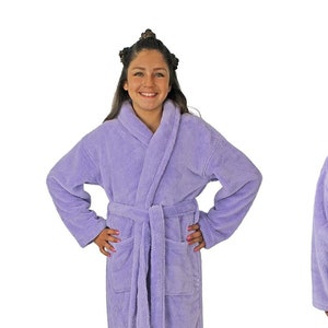 May include: A light purple terry cloth robe with a shawl collar, long sleeves, and a waist tie. The robe has two front pockets and is shown from the front and back. The model is wearing the robe.