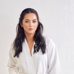 May include: A white waffle weave robe with a shawl collar and a tie belt. The robe has two patch pockets.