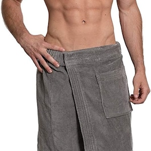 May include: A grey terry cloth wrap towel featuring an elasticated waistband, a secure front closure, and a single patch pocket on the right side. The fabric has a textured, absorbent surface and falls to just above the knee in length.