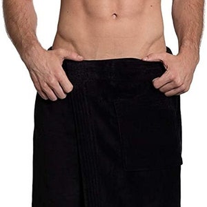 May include: A solid black wrap-around towel featuring a textured fabric surface, a straight hemline, and a large square patch pocket on the front right side. The towel is secured at the waist with a simple overlapping design and a clean finish.
