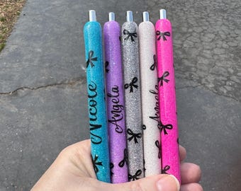 May include: Five glitter pens with black bows and personalized names: Nicole, Angela, Anna, Ashley, and Sarah.