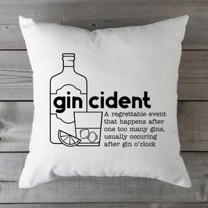 May include: White throw pillow with black text and a graphic of a bottle of gin and a glass of gin with ice and a lime wedge. The text reads "gin cident" and "A regrettable event that happens after one too many gins, usually occurring after gin o'clock."
