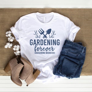 May include: White t-shirt with a blue graphic of crossed gardening tools and the text "GARDENING forever (HOUSEWORK WHENEVER)".