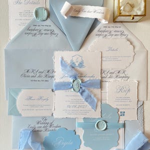 Set di inviti di nozze fatti a mano blu polveroso, inviti di carta con bordo increspato, fiori di carta di cotone, piante, sigilli di cera, nastro strappato