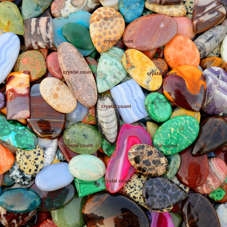 May include: A collection of colourful, polished, and natural stones. The stones are various shapes and sizes, including oval, round, and rectangular. The stones are arranged in a random pattern, creating a visually appealing display.