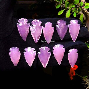May include: Ten pink arrowhead shaped crystal points. The points are translucent and have a smooth, polished finish.
