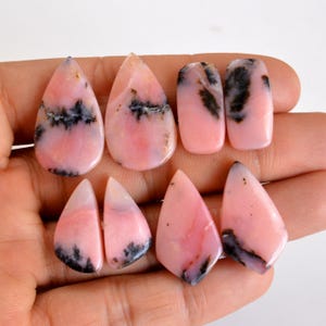 May include: Six pink and black gemstone cabochons, two rectangular and four teardrop shaped, for jewelry making.