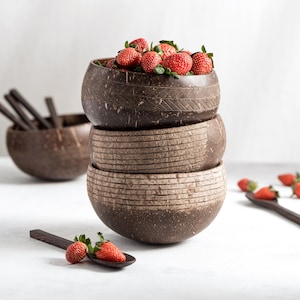 Puede incluir: Tres cuencos de coco marrón apilados con un borde, llenos de fresas rojas frescas. Los cuencos tienen un aspecto natural y rústico y son perfectos para servir aperitivos o ensaladas.