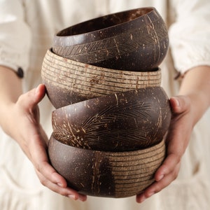 May include: A set of four brown coconut bowls stacked on top of each other. The bowls have different patterns carved into them.