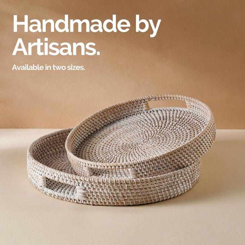 May include: Two white woven wicker trays with handles. The trays are round and have a natural woven pattern. The text "Handmade by Artisans. Available in two sizes." is displayed above the trays.